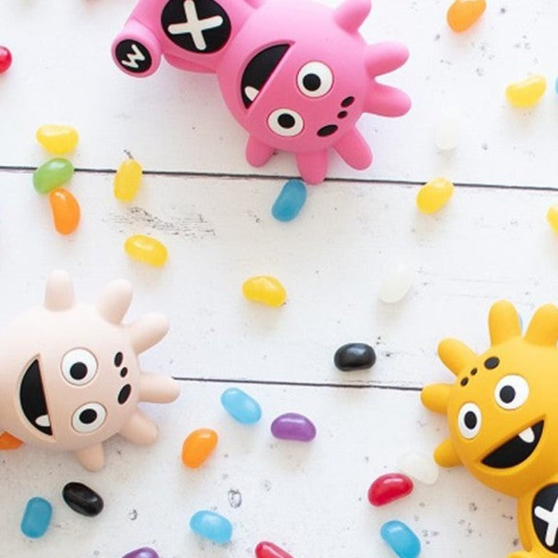 Mibblers Silicone Teether - 100% Latex-Free, Safe, and Adorable Teething Toy. Mibblers on white wooden board with jellybeans.