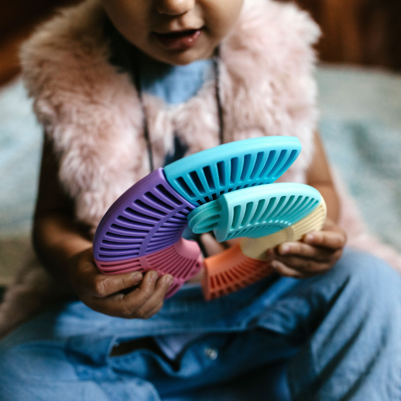 Jellystone Designs Rainbow Colour Wheel, a baby sensory puzzle toy that's free from BPA, phthalates, PVC, cadmium, and lead. Stimulate your baby's color recognition and development while ensuring safety. Child playing with the colour wheel in pastel colours.