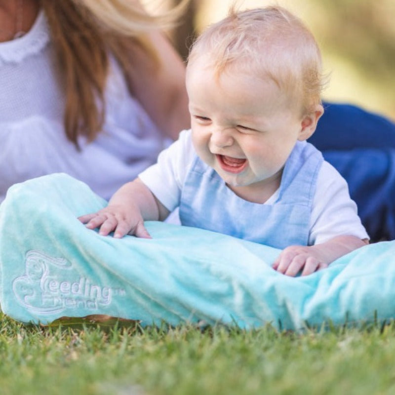Feeding Friend Nursing Pillow - The Perfect Gift for Hassle-Free Baby Feeding. Baby leaning on pillow at the park.