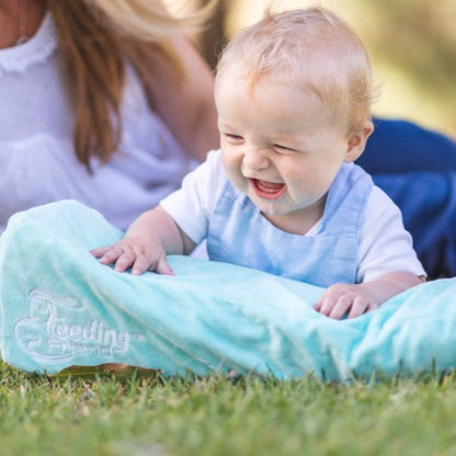 Feeding Friend Nursing Pillow - The Perfect Gift for Hassle-Free Baby Feeding. Baby leaning on pillow at the park.