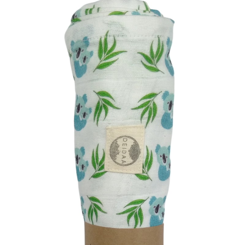 Wrap your baby in pure comfort with our GOTS certified organic cotton muslin swaddle. Ethically made and toxin-free, our breathable swaddle is perfect for newborns. Koala design on white background.