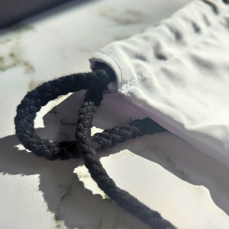 White drawstring bag with black strings and gaming design.