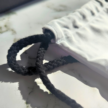 White drawstring bag with black strings and gaming design.