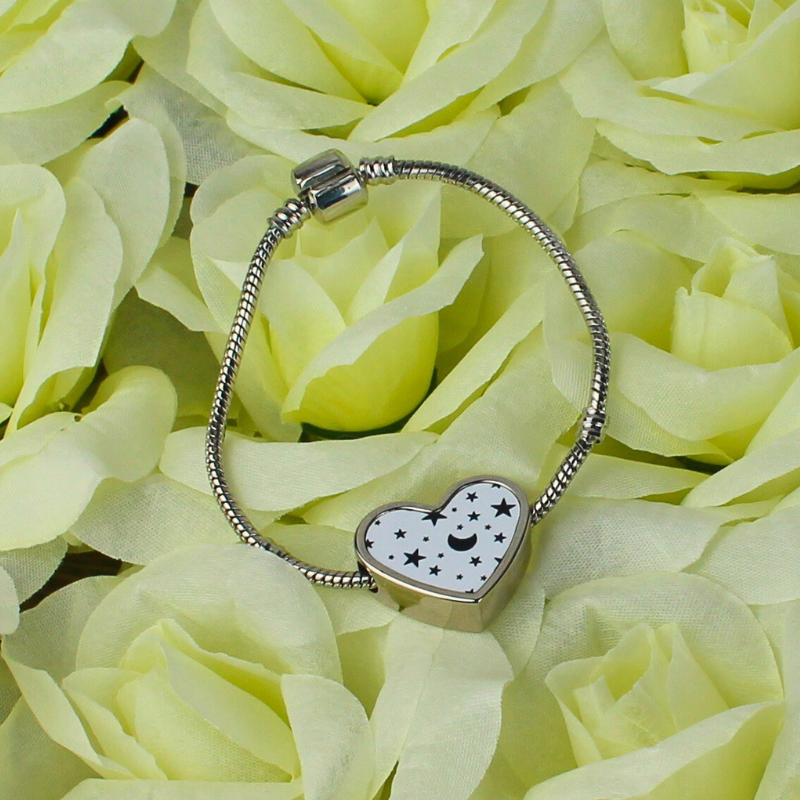 Heart shaped charm with moon and stars black and white print and silver charm bracelet.