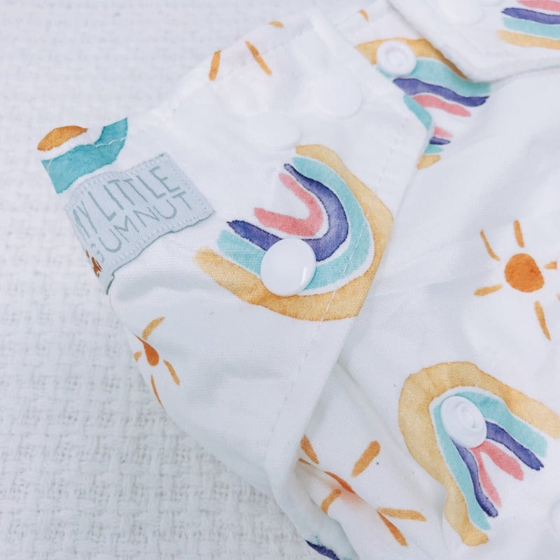 Switch to eco-friendly Modern Cloth Nappies (MCNs) for babies. Up-close pastel rainbows design