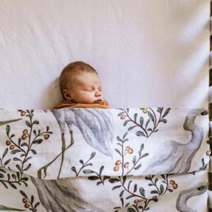 Discover our collection of gorgeous 100% organic cotton muslin swaddles that are lightweight, breathable, and machine washable. Baby using crane swaddle as blanket in cot.