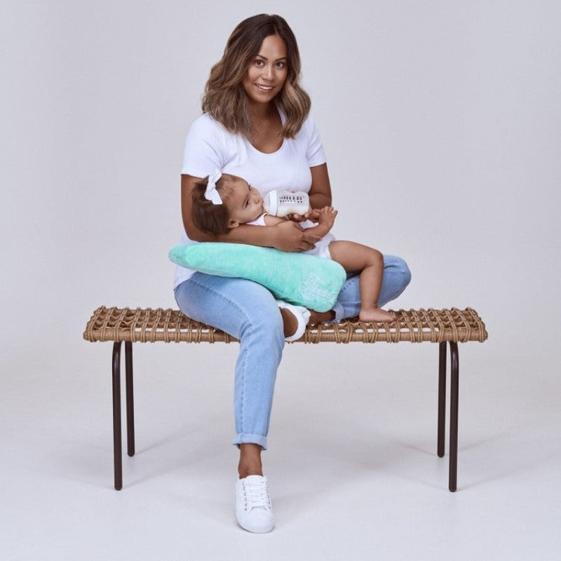 Feeding Friend Nursing Pillow - The Perfect Gift for Hassle-Free Baby Feeding. Woman bottle feeding baby on a bench.