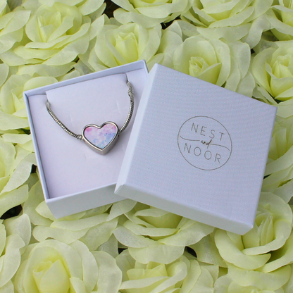 Heart-shaped charm with pink and blue pastel print and silver bracelet in a white gift box.