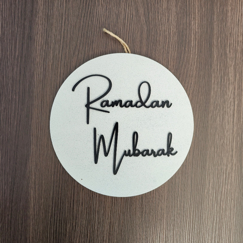 Round white sign with 'Ramadan Mubarak' text on a wooden surface