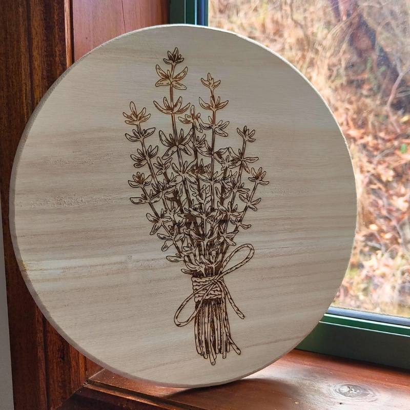 Round natural wooden plaque with engraved thyme bunch design.