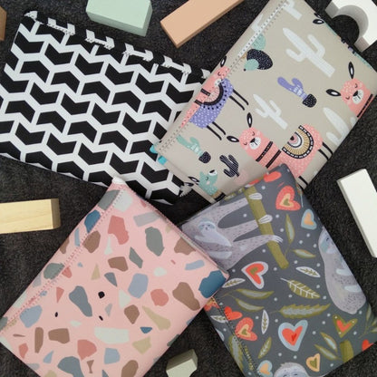 Discover convenience with our Water-Resistant Neoprene Change Mat Clutch. 4 designs displayed in a flatlay with wooden blocks.