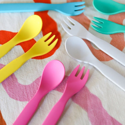 Free from melamine, and biodegradable and compostable, our plant-based spoon and fork cutlery set makes mealtimes (and sneaky snacks) way more fun! 5 colours of cutlery sets displayed on a tea towel.