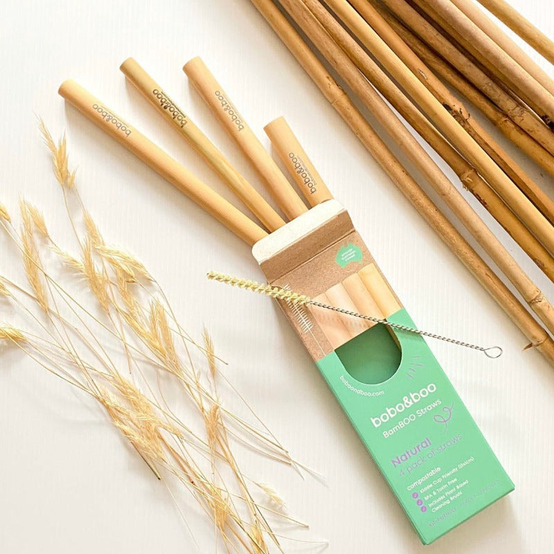 BamBOO Reusable Straws, 4 pack displayed with free straw cleaner next to packaging box, displayed next to bamboo sticks.