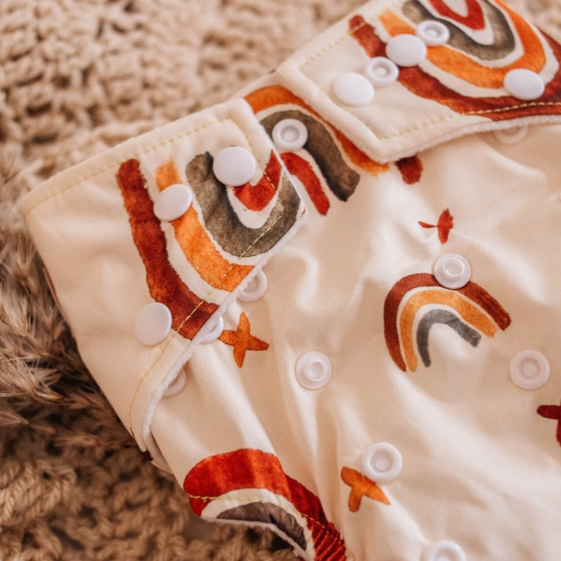 Switch to eco-friendly Modern Cloth Nappies (MCNs) for babies. Close-up of earth tones rainbow design.