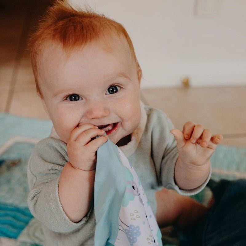 Introducing Cuddle Soother: The perfect blend of comfort and teething relief. Sleepy Bear design laid flat on a plain white background. Baby holding sleeping bear design, chewing on teether.