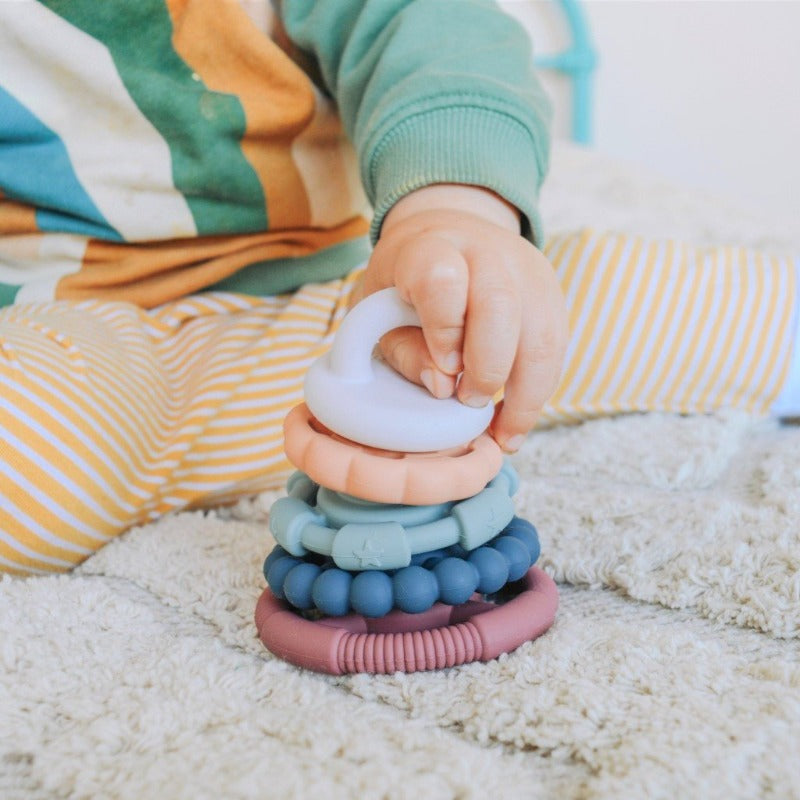 Jellystone Designs Rainbow Teething Ring Stacker - Multi-Purpose Toy for Soothing and Stacking. Child playing with ring stacker on carpet.