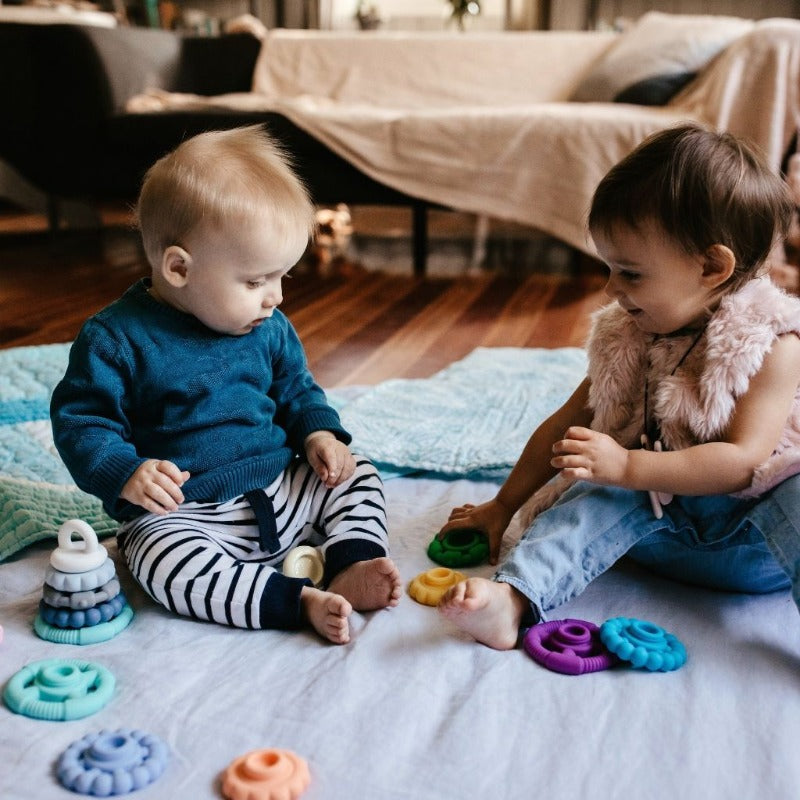 Jellystone Designs Rainbow Teething Ring Stacker - Multi-Purpose Toy for Soothing and Stacking. Two children playing with ring stackers on a play mat.