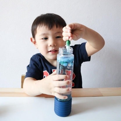 Elevate play with our DIY Sensory Bottle Kit. Small boy filling the blue bottle