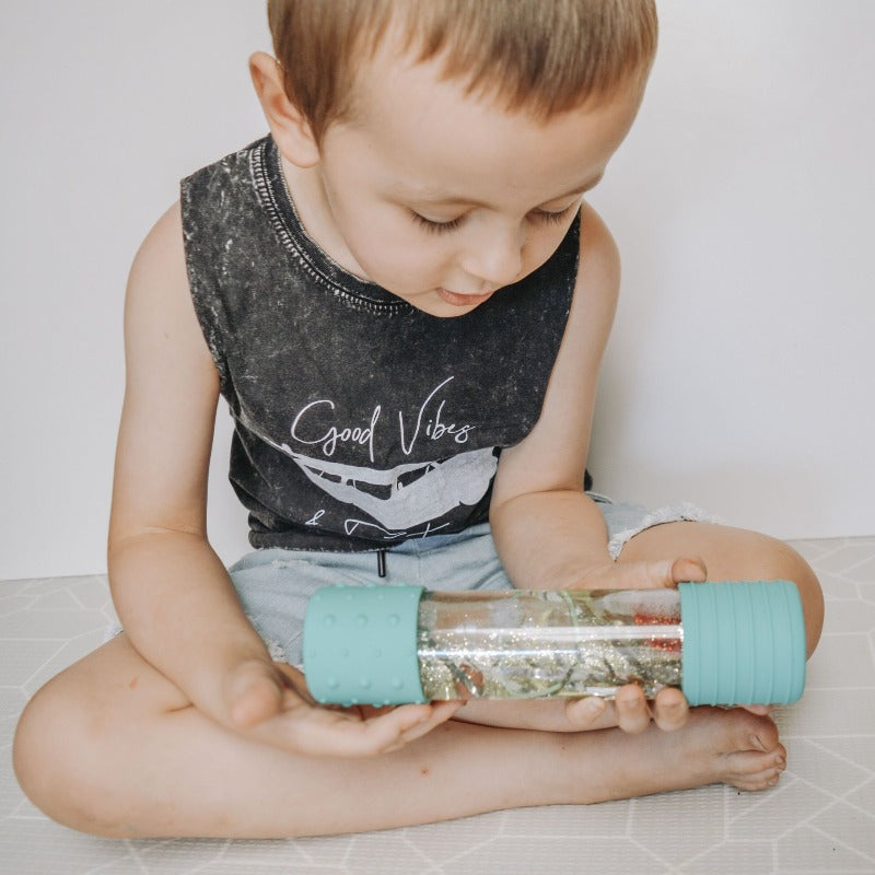 Elevate play with our DIY Sensory Bottle Kit. Small boy playing with light blue sensory bottle