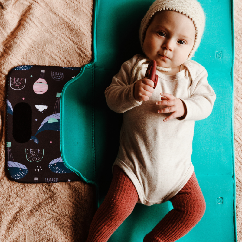 Discover convenience with our Water-Resistant Neoprene Change Mat Clutch. Lifestyle image with baby on mat