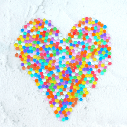 Discover our vibrant rainbow water beads! These reusable and certified water beads provide hours of sensory play. Non-toxic, biodegradable, and safe for kids above 5. Hydrated water beads displayed in a heart shape.