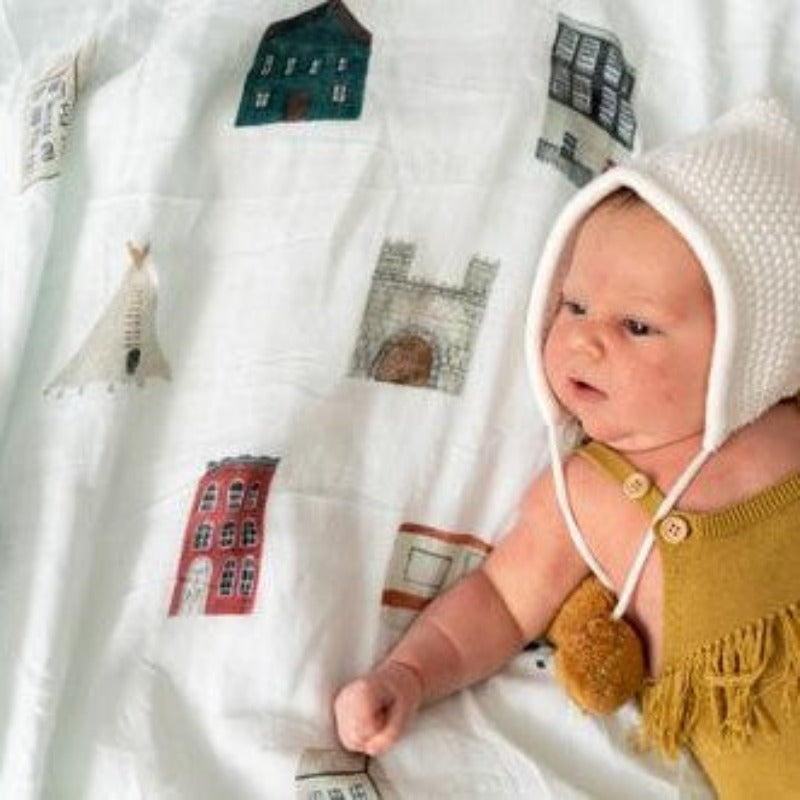 Discover our collection of gorgeous 100% organic cotton muslin swaddles that are lightweight, breathable, and machine washable. Baby laying on ole houses design swaddle.